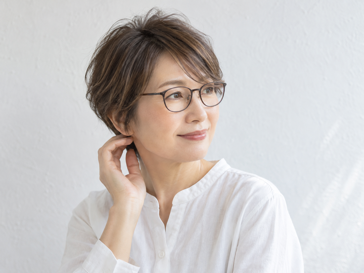 細いフレームのメガネと軽い前髪を合わせた50代女性の自然なショート