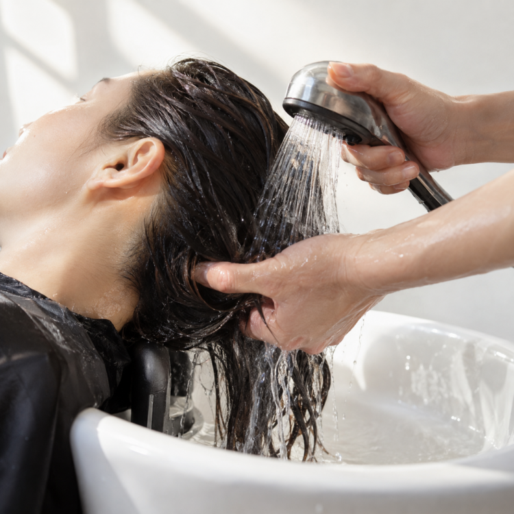 髪を分けながら後頭部とえり足の内側へお湯を通してすすぐ様子