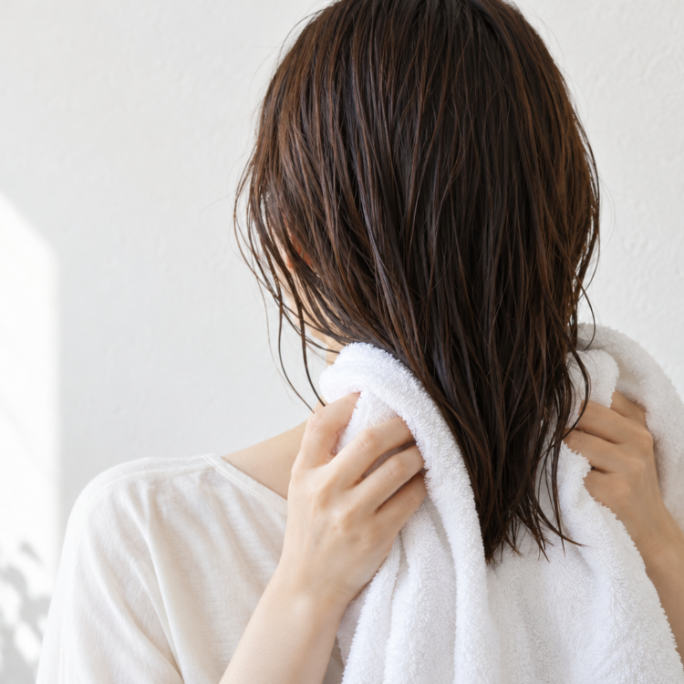 湿った髪の毛先を柔らかなタオルで挟んで押さえる手元