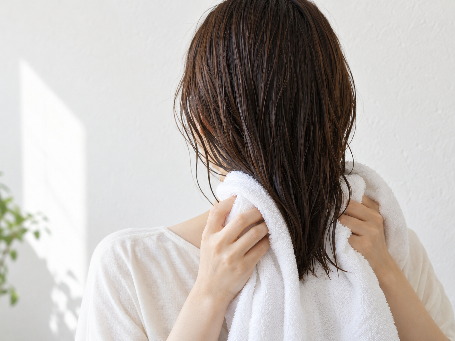 湿った髪の毛先を柔らかなタオルで挟んで押さえる手元
