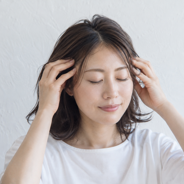 指の腹をこめかみ付近の頭皮へ軽く当てるセルフケアの様子